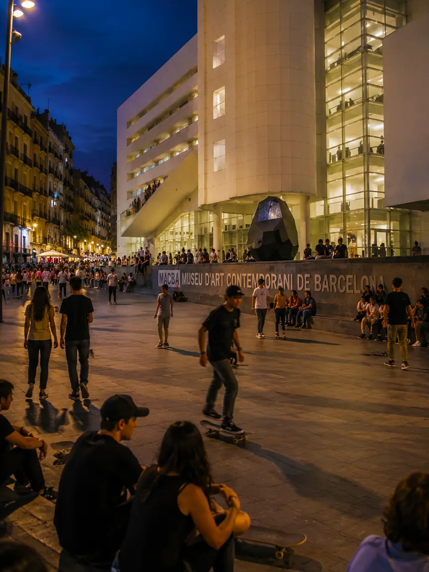 Barcelona Museum Night 2026: Skateboarder riding across the illuminated plaza in front of the MACBA Museu d'Art Contemporani de Barcelona at night, with crowds of people relaxing and socializing on the steps and pavement.