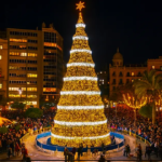 Massive golden spiral Christmas tree glowing brightly in Plaza del Ayuntamiento surrounded by crowds and a carousel at Christmas Events in Valencia.